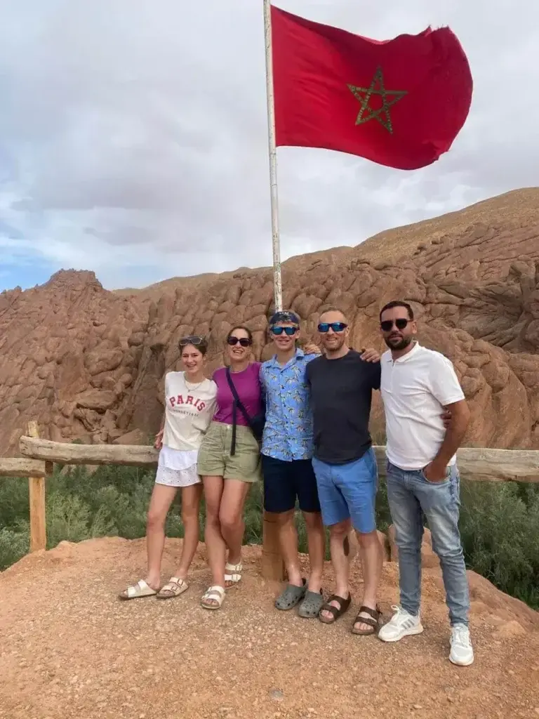 Safe & Trust Travel driver with clients beside the Moroccan flag